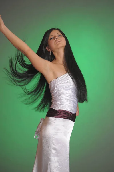 Menina morena em um vestido branco longo no estúdio em um bac verde — Fotografia de Stock