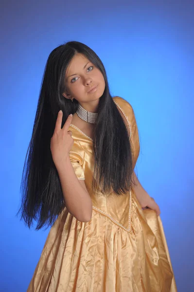ブルネットの女の子で長い黄金のドレスでザ・スタジオ — ストック写真