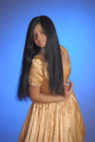 Μελαχρινή κοπέλα σε ένα μακρύ χρυσό φόρεμα στο στούντιο — Φωτογραφία Αρχείου