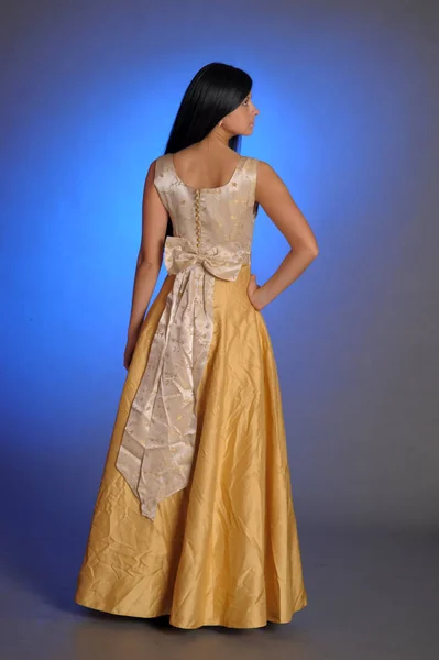 Brunettjente i lang, gyllen kjole i studio – stockfoto