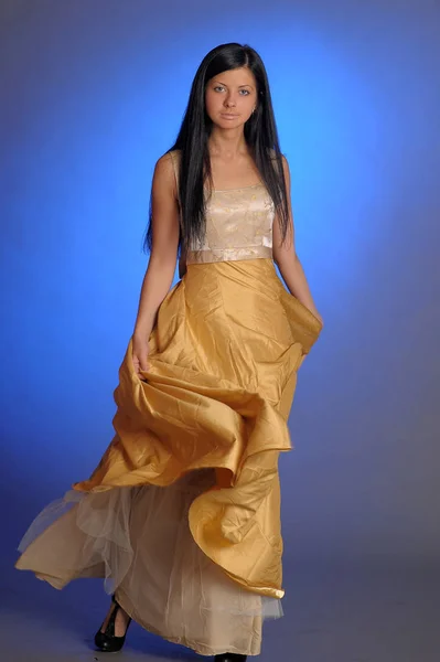 ブルネットの女の子で長い黄金のドレスでザ・スタジオ — ストック写真