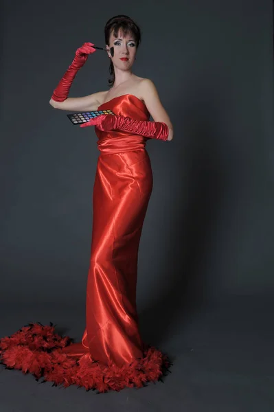 Брюнетка в длинном красном платье на сером фоне в студии — стоковое фото