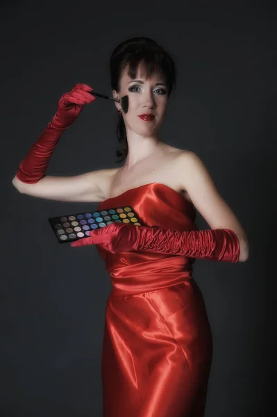 Брюнетка в довгій червоній сукні на сірому фоні в студії — стокове фото