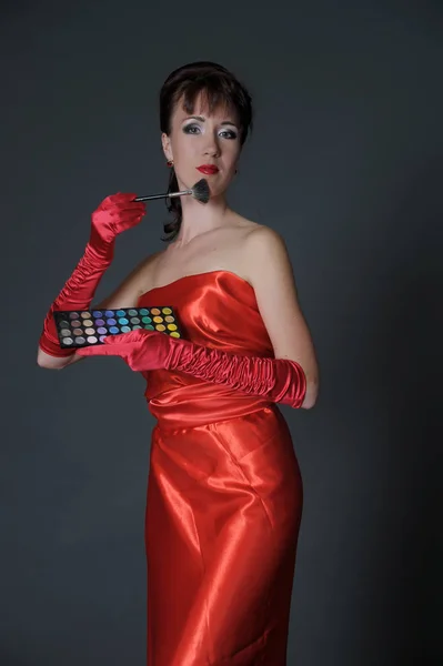 Brunette in a long red dress on a gray background in the studio — 스톡 사진