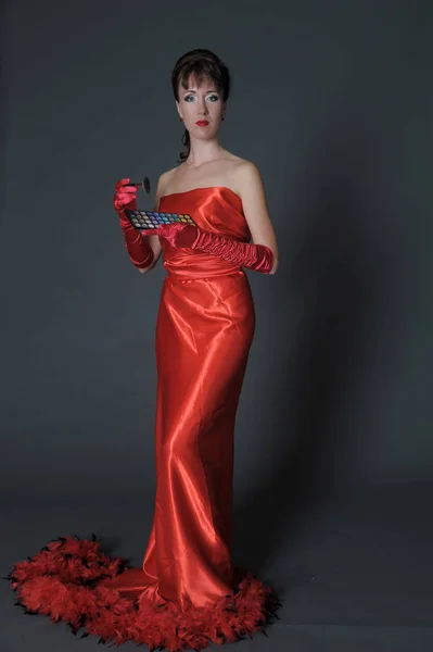 Brunetka w długiej czerwonej sukience na szarym tle w studio — Zdjęcie stockowe