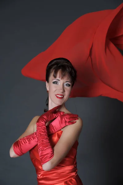 Brunette in een rode jurk op een grijze achtergrond in de studio en f — Stockfoto