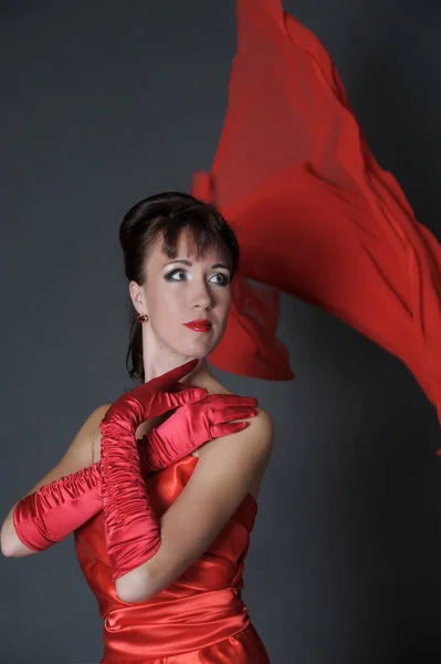 Morena en un vestido rojo sobre un fondo gris en el estudio y f — Foto de Stock