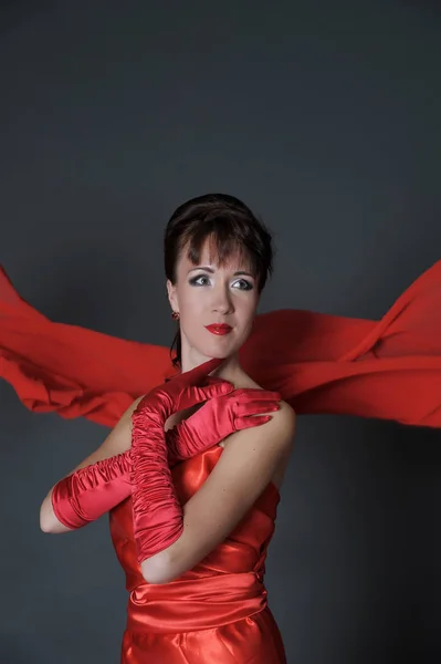 Brunette in a red dress on a gray background in the studio and f — Stock Photo, Image