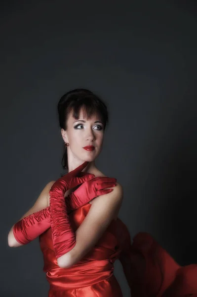 Brunette in een rode jurk op een grijze achtergrond in de studio en f — Stockfoto