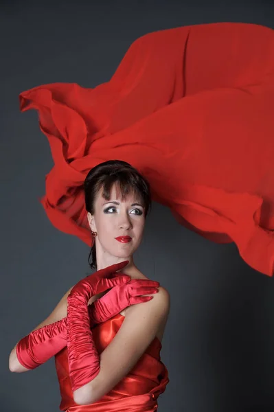 Morena en un vestido rojo sobre un fondo gris en el estudio y f — Foto de Stock