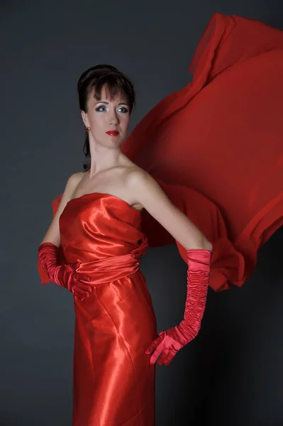 Brunette in a red dress on a gray background in the studio and f — Stock Photo, Image