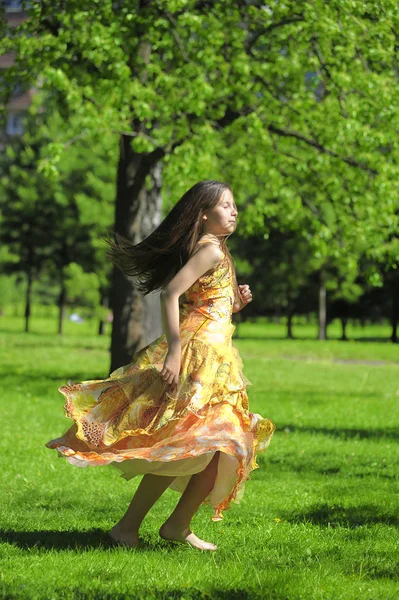Κορίτσι σε ένα πορτοκαλί φόρεμα γυρίζει, τρέχει το καλοκαίρι στην p — Φωτογραφία Αρχείου