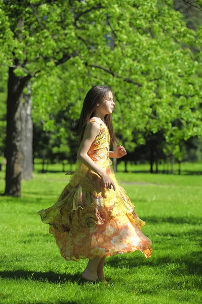 Menina em um vestido laranja está girando, corre no verão no p — Fotografia de Stock