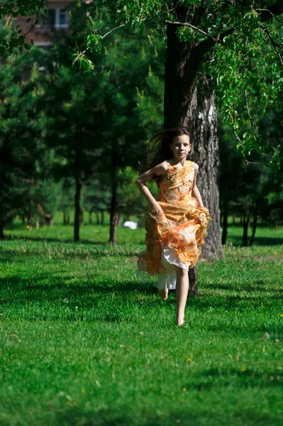 Menina em um vestido laranja está girando, corre no verão no p — Fotografia de Stock