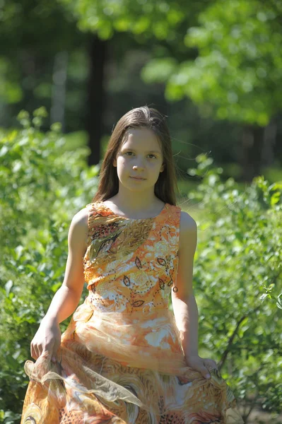 Mädchen in orangefarbenem Kleid dreht sich, läuft im Sommer in der Sonne — Stockfoto