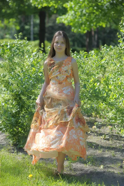 Chica en un vestido naranja está girando, corre en el verano en el p — Foto de Stock