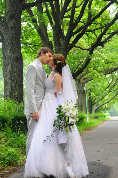 Heureux jeunes mariés avec un bouquet de fleurs ensemble sur leur wedd — Photo