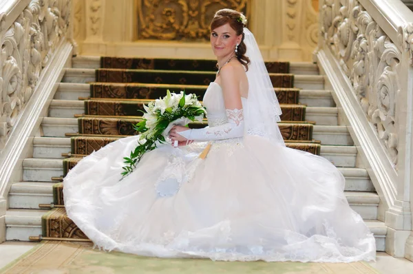 Bride with a bouquet in a wedding dress sits — 스톡 사진