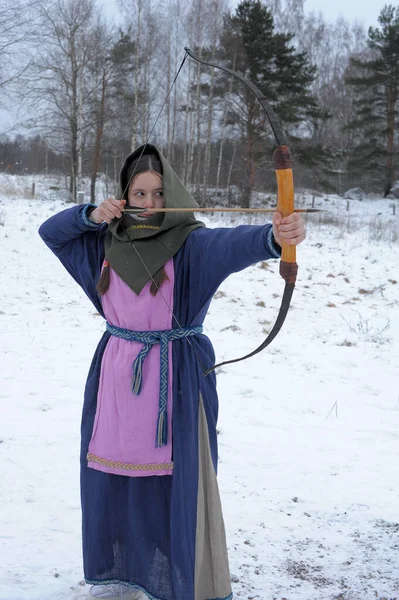 A girl shoots in the winter from a bow at the festival of mediev — Stock Photo, Image