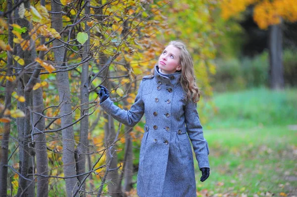Dziewczyna w szarym płaszczu w parku — Zdjęcie stockowe