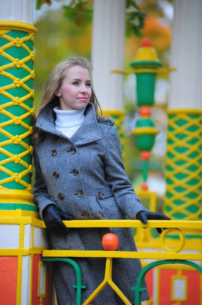 Девушка в сером пальто в осеннем парке на мосту — стоковое фото