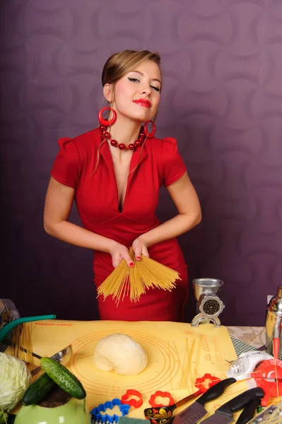 Σέξι νοικοκυρά σε ένα κόκκινο φόρεμα με ζυμαρικά — Φωτογραφία Αρχείου