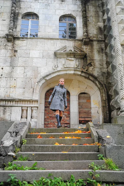 Meisje in een grijze jas op de trap van een stenen trap — Stockfoto