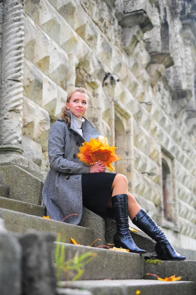 Ragazza in un cappotto grigio sui gradini di una scala di pietra — Foto Stock