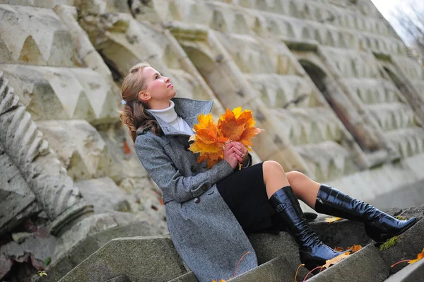 Meisje in een grijze jas op de trap van een stenen trap — Stockfoto