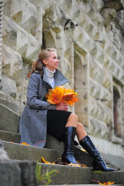 Menina em um casaco cinza nos passos de uma escada de pedra — Fotografia de Stock