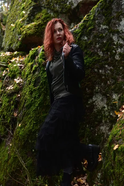 Κοκκινομάλλα Γυναίκα Μαύρο Δερμάτινο Μπουφάν Στο Δάσος Φόντο Από Πέτρα — Φωτογραφία Αρχείου