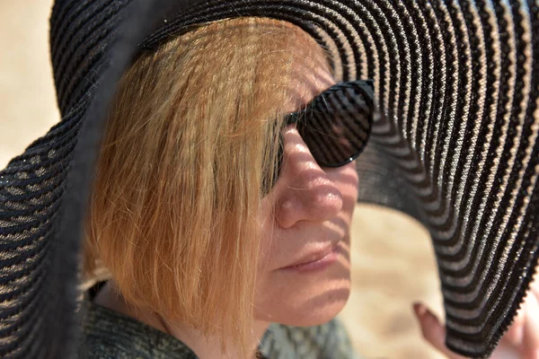 サングラスをかけた中年ブロンドの女性の肖像画とつばの広い帽子 — ストック写真