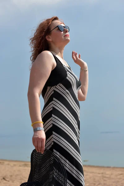 穿着条纹连衣裙的中年妇女 背景在大海中 — 图库照片