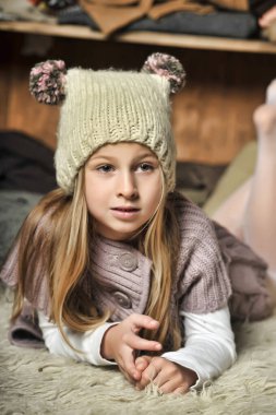 blonde girl in knitted clothes and a hat with pompons clipart