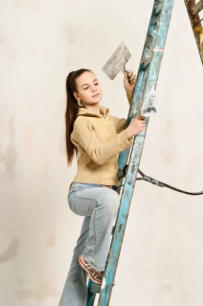 黑发少女 忙着修理梯子上的公寓 — 图库照片