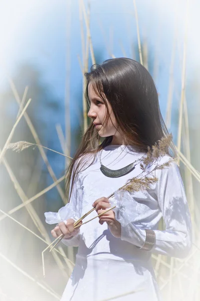 春の高い乾いた草の間に白い服を着た女の子 — ストック写真