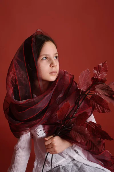Stüdyodaki Esmer Kız Elinde Sonbahar Yapraklarıyla Kırmızı Arka Planda — Stok fotoğraf