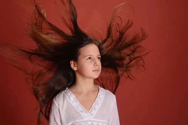 ブルネット子供女の子でスタジオでA赤背景に飛んで髪 — ストック写真