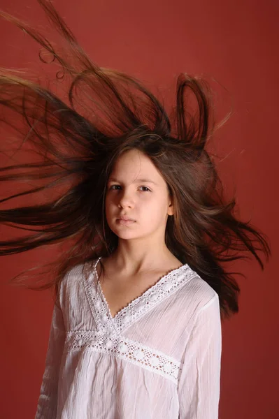 Brunette Kind Meisje Studio Een Rode Achtergrond Met Vliegend Haar — Stockfoto