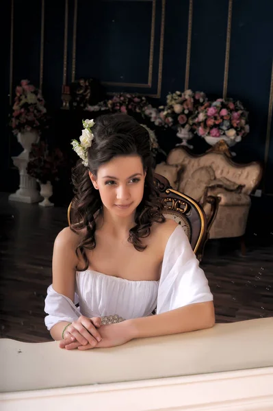 穿着白色衣服坐在镜子旁边的椅子上的漂亮优雅的姑娘 — 图库照片
