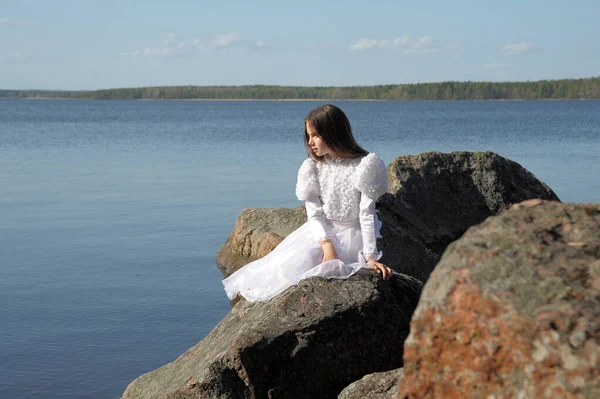 Młoda Dziewczyna Białej Sukience Siedzi Pobliżu Wody Kamieniach — Zdjęcie stockowe