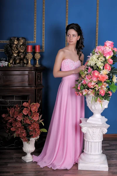 Jong Brunette Meisje Een Roze Elegante Jurk Tussen Bloemen Kamer — Stockfoto