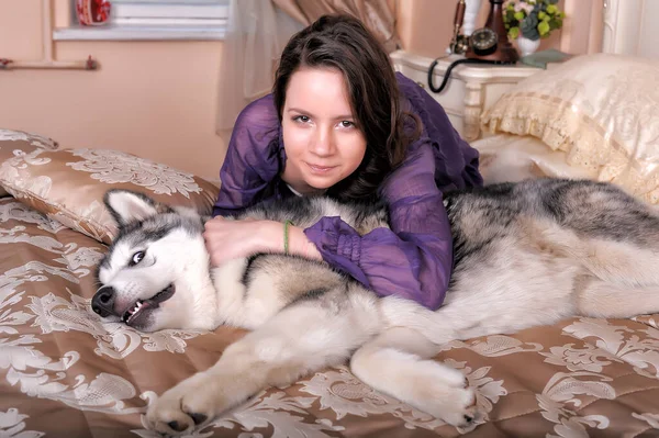 Jovem Menina Vestido Lilás Com Seu Malamute Cama — Fotografia de Stock