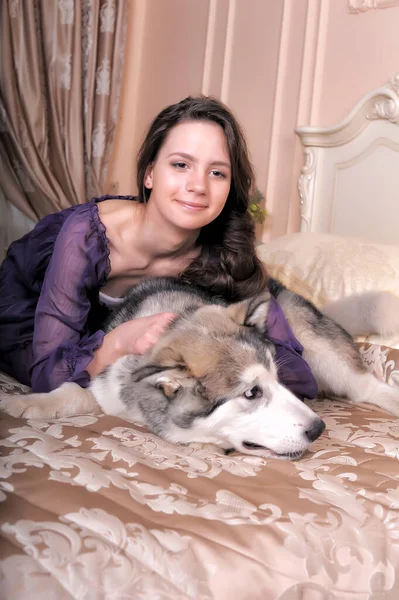 Jovem Menina Vestido Lilás Com Seu Malamute Cama — Fotografia de Stock