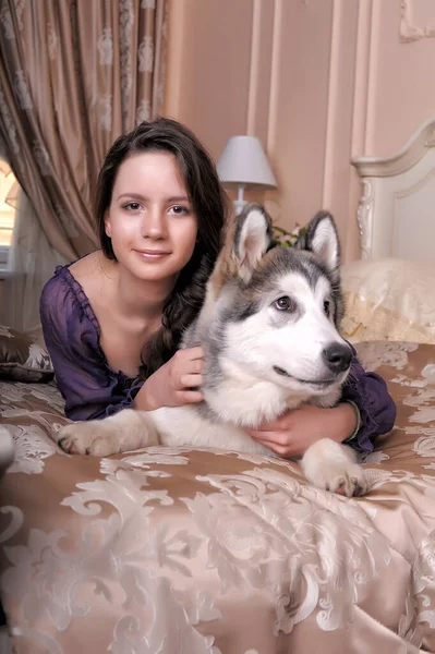 Jovem Menina Vestido Lilás Com Seu Malamute Cama — Fotografia de Stock