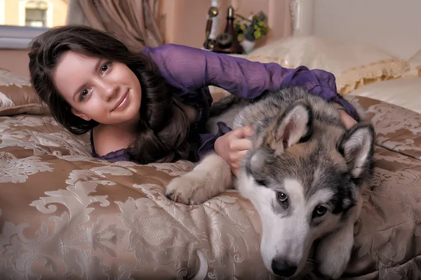 Jovem Menina Vestido Lilás Com Seu Malamute Cama — Fotografia de Stock