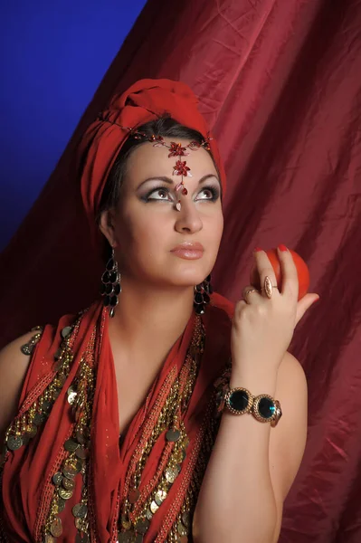 Piękna Brunetka Kobieta Czerwonych Orientalnych Ubrań Turbanem Biżuterią Głowie Jabłko — Zdjęcie stockowe