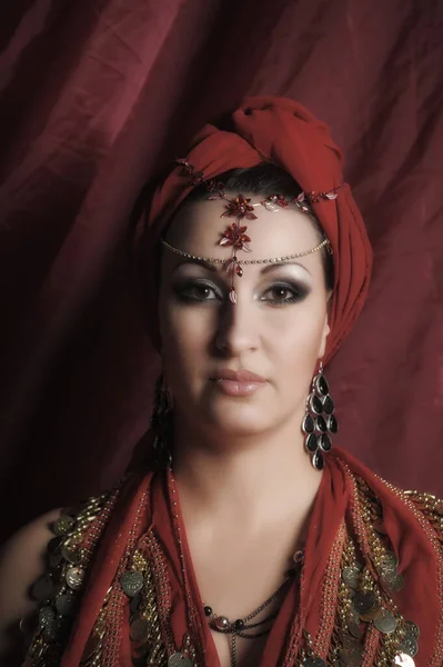 漂亮的黑发女人 穿着红色东方服装 头上戴头巾 头上戴着珠宝 — 图库照片