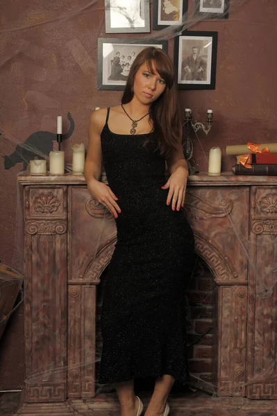 壁炉边穿着黑色衣服的漂亮的黑发女人 — 图库照片