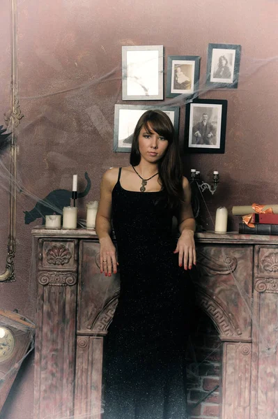 暖炉のそばの黒いドレスの美しいブルネットの女性 — ストック写真